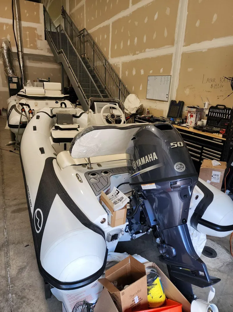 Slide: The Image of 2025 Walker Bay Generation 13 LTE inflatable boat with Yamaha 50 outboard motor in a garage. - 2