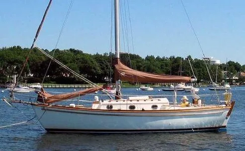 Slide: The Image of 1979 Shannon 28 sailboat anchored on a calm lake with trees in the background. - 0