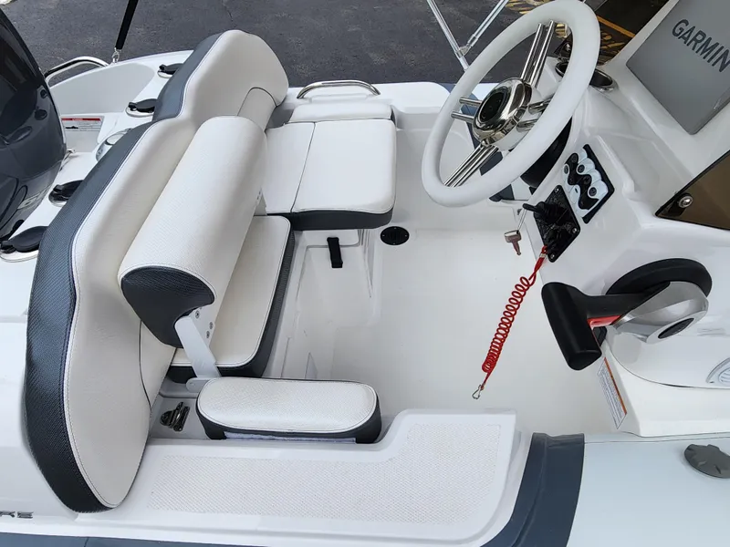 Slide: The Image of 2025 Walker Bay Venture 13 boat cockpit with white and black seating, steering wheel, and Garmin navigation. - 6