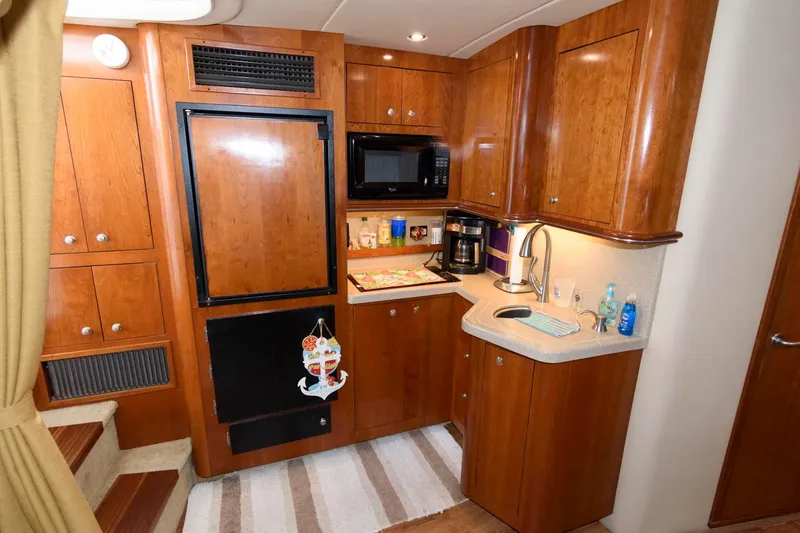 Slide: The Image of 2004 Cruisers Yachts 370 Express kitchen with wooden cabinets, microwave, and sink. - 10
