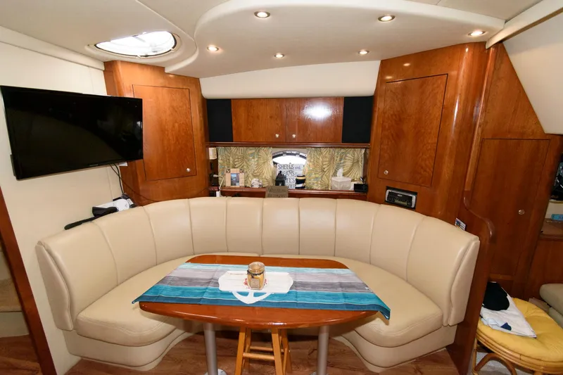 Slide: The Image of 2004 Cruisers Yachts 370 Express interior with curved seating, wooden table, and mounted TV. - 11
