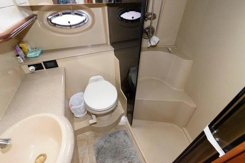 Slide: The Image of 2004 Cruisers Yachts 370 Express bathroom with shower, toilet, sink, and porthole window. - 14