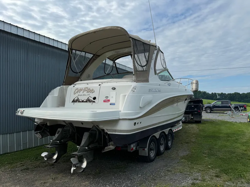 Slide: The Image of 2005 Four Winns 328 Vista boat on trailer, parked outdoors near a metal building. - 1