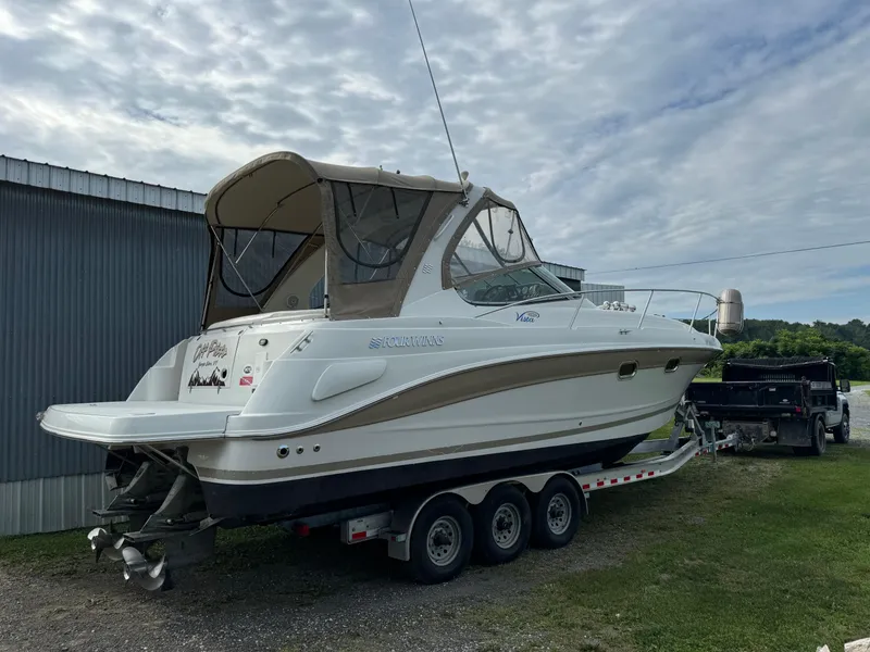 Slide: The Image of 2005 Four Winns 328 Vista boat on a trailer, parked outdoors near a building. - 2
