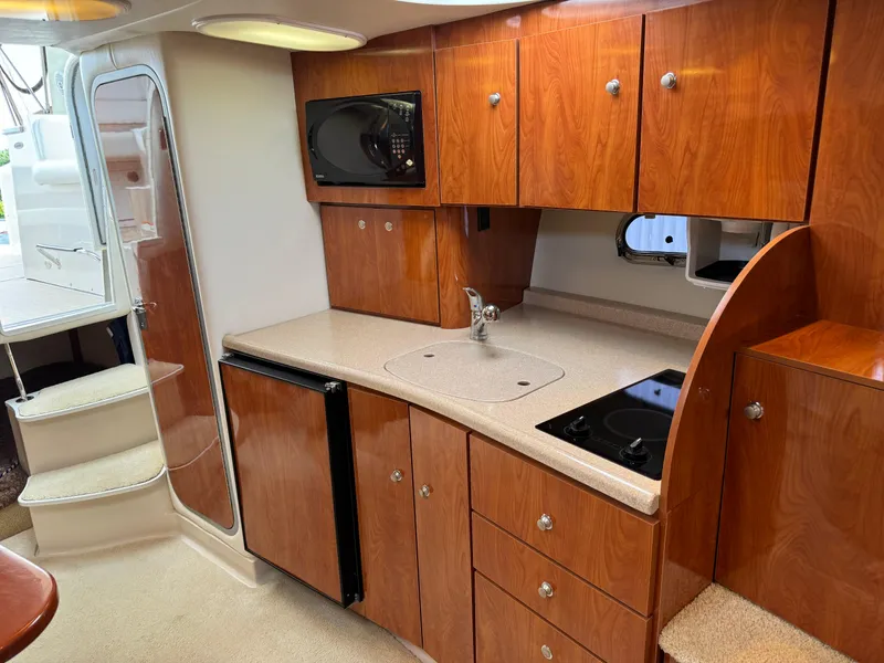Slide: The Image of 2005 Four Winns 328 Vista yacht interior with kitchenette, featuring wood cabinets and modern appliances. - 22