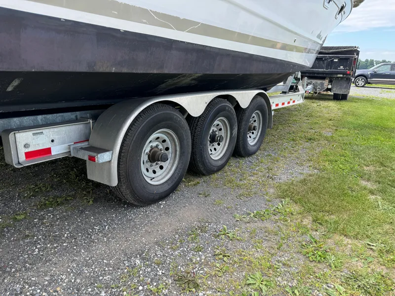 Slide: The Image of 2005 Four Winns 328 Vista boat on a triple-axle trailer, parked on grass. - 33