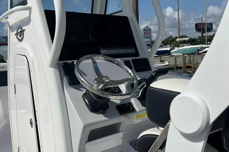 Slide: The Image of 2024 Tidewater 232 CC Adventure boat helm with steering wheel and controls. - 8