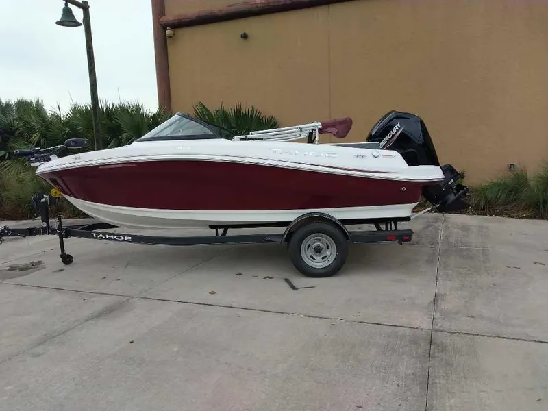 The Image of 2024 Tahoe 185 S boat on trailer, red and white design, parked outdoors. - 0