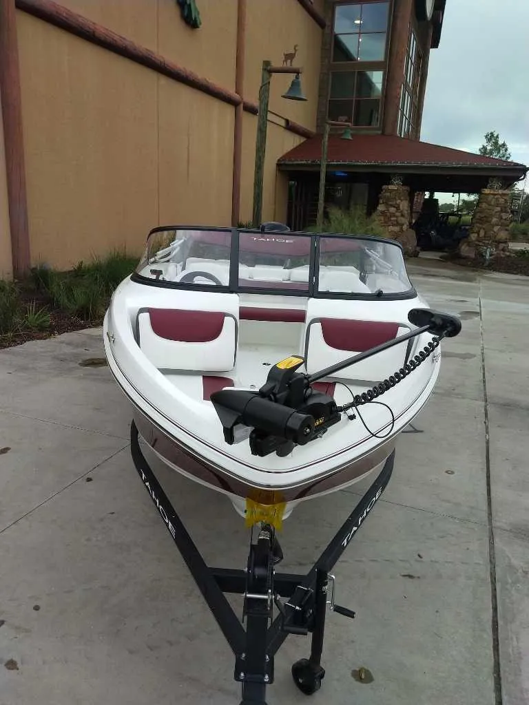Slide: The Image of 2024 Tahoe 185 S boat with maroon interior, parked outdoors. - 1