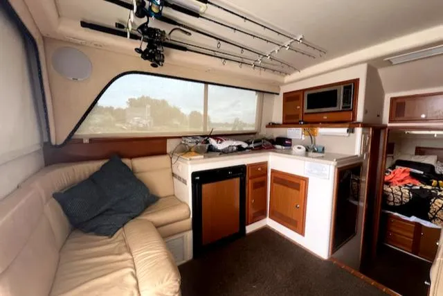 Slide: The Image of Interior of a 2002 Cabo 35 Flybridge with kitchenette, seating area, and fishing rods. - 17