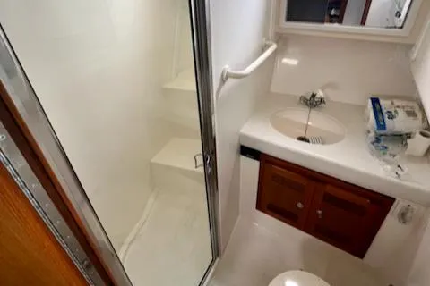 Slide: The Image of 2002 Cabo 35 Flybridge bathroom with shower, sink, and wooden cabinets. - 19