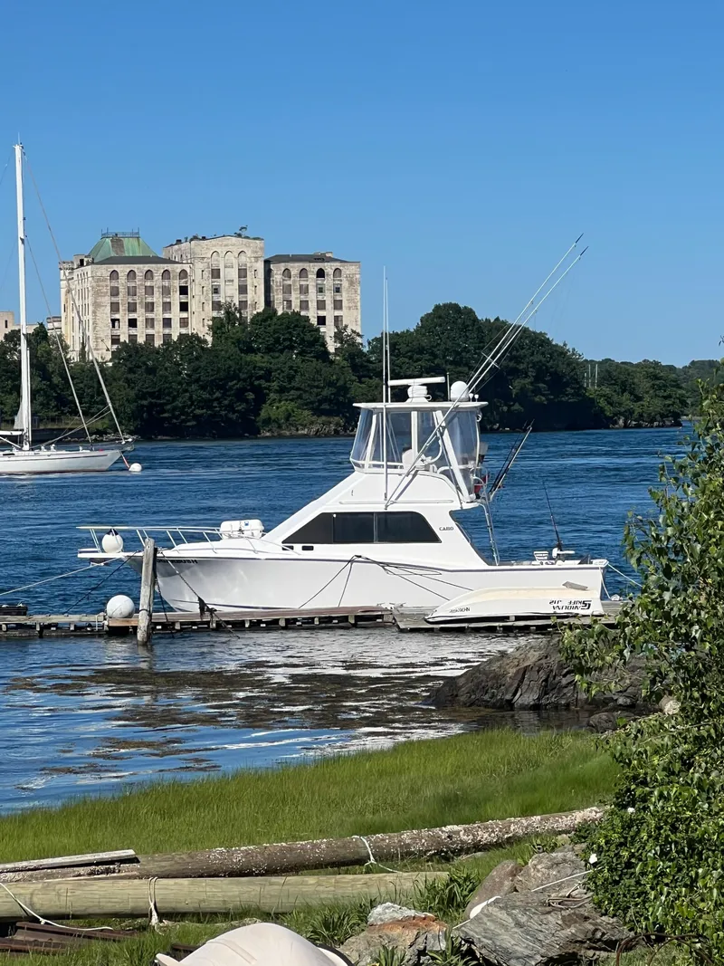 Slide: The Image of 2002 Cabo 35 Flybridge boat docked by the shore with buildings in the background. - 36