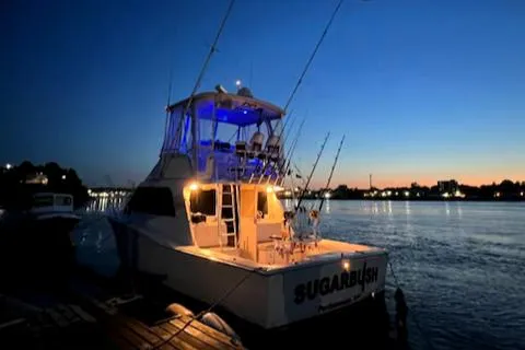 Slide: The Image of 2002 Cabo 35 Flybridge boat docked at sunset with illuminated deck. - 4