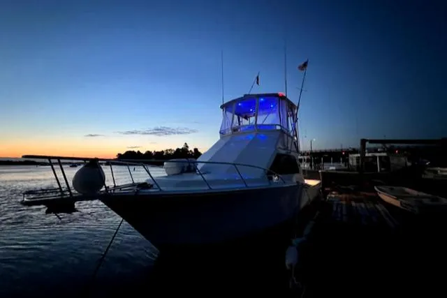 Slide: The Image of 2002 Cabo 35 Flybridge boat docked at sunset with blue lights. - 5