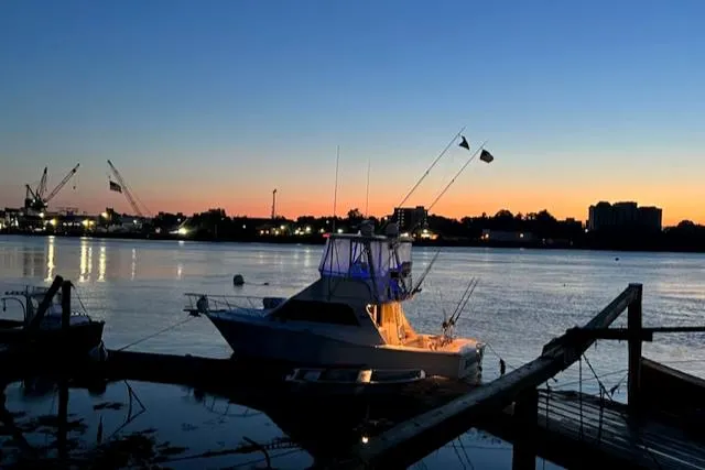 Slide: The Image of 2002 Cabo 35 Flybridge boat docked at sunset with city skyline in the background. - 6