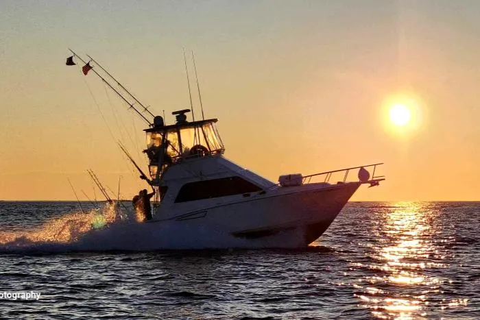 Slide: The Image of 2002 Cabo 35 Flybridge boat cruising at sunset on the ocean. - 7