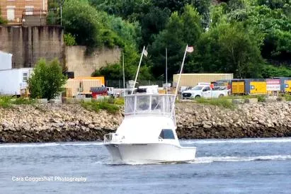 Slide: The Image of 2002 Cabo 35 Flybridge boat cruising near industrial shoreline. - 9