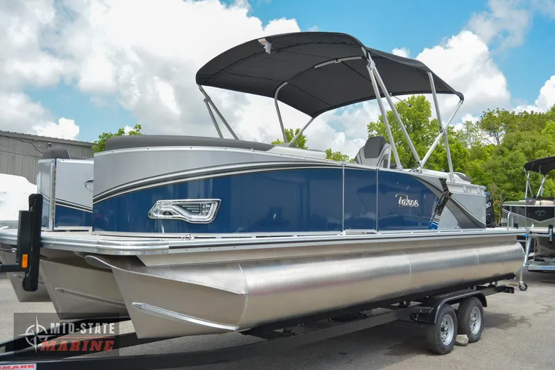 Slide: The Image of 2024 Tahoe Pontoon LTZ Quad Lounger on trailer, blue and silver, with canopy. - 0