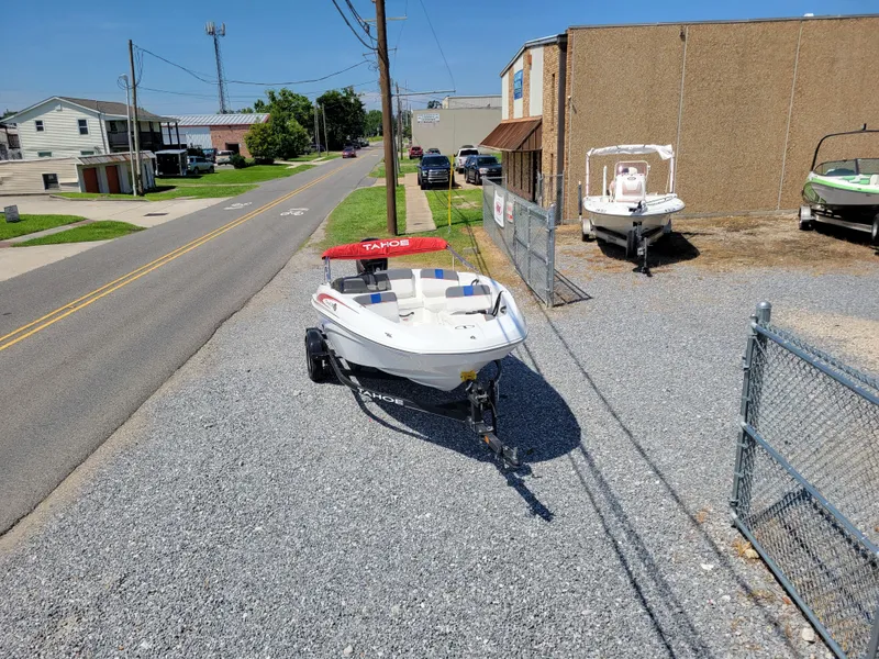Slide: The Image of 2024 Tahoe T16 boat on a trailer in a gravel lot near a road. - 8