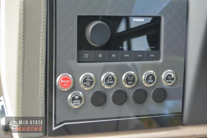 Slide: The Image of 2024 Tahoe Pontoon Cascade Elite Windshield control panel with Fusion stereo system and various function buttons. - 23