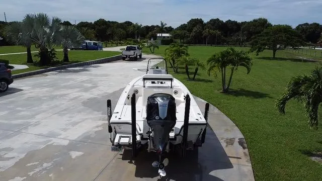 Slide: The Image of 2022 Pathfinder 2300 HPS boat parked on a driveway with green lawn and trees. - 4