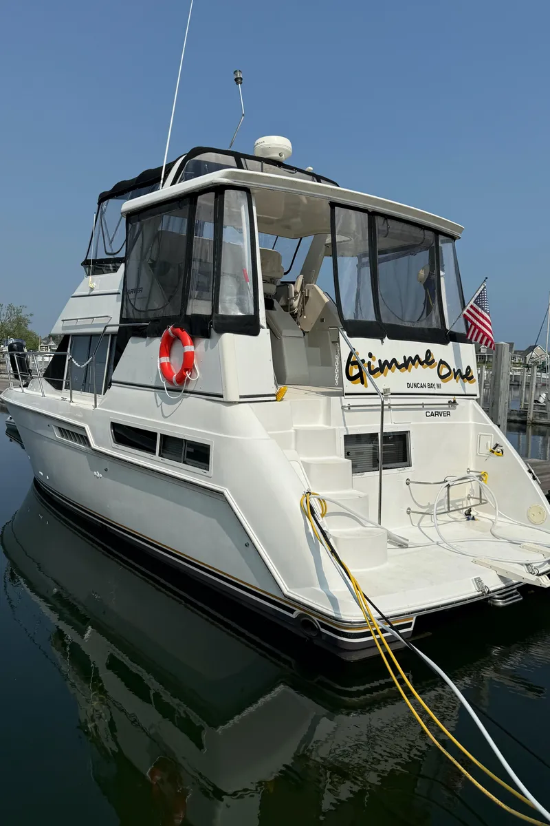 Slide: The Image of 1997 Carver 355 Main Ship Aft Cabin yacht docked, featuring a white exterior and American flag. - 23