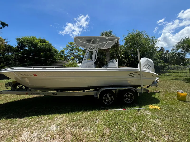 Slide: The Image of 2023 ALK2 Powerboats 25 CRX on trailer, parked on grass under clear blue sky. - 0