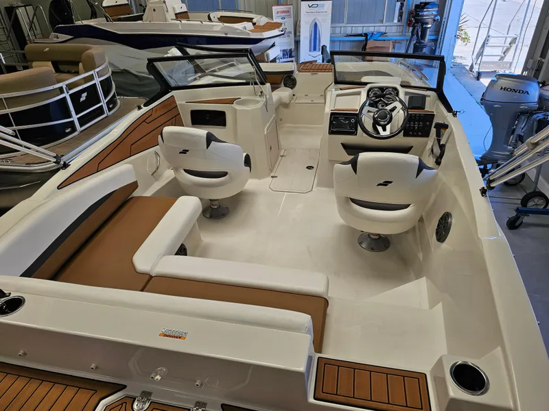 Slide: The Image of 2024 Starcraft SVX 210 OB DC boat interior with seating and steering console. - 2