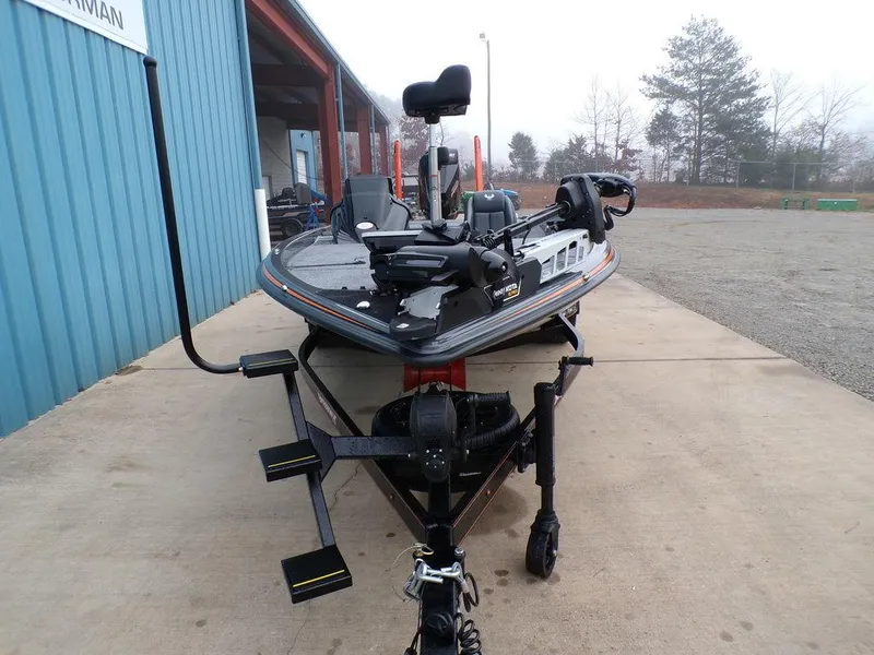 Slide: The Image of 2025 Phoenix 920 Elite fishing boat on trailer, parked outside a blue building. - 33