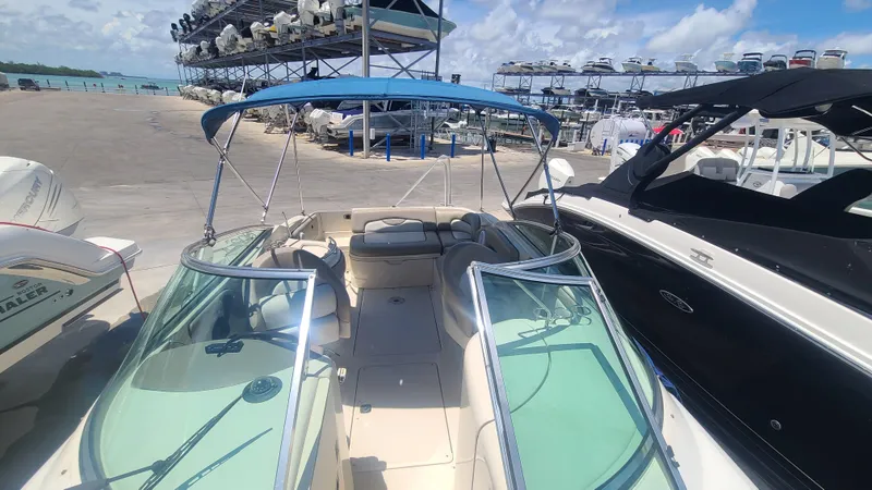 Slide: The Image of 2004 Sea Ray 270 Sundeck boat docked with blue bimini top, surrounded by other boats. - 7