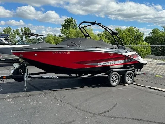 The Image of 2016 Scarab 215 HO Impulse boat on trailer, red and black, parked outdoors. - 1