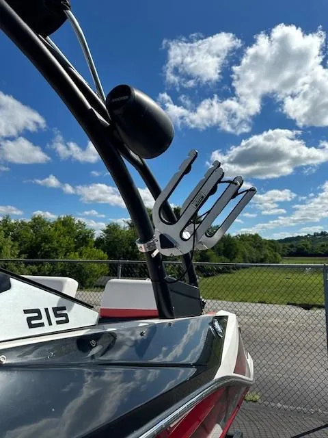 Slide: The Image of 2016 Scarab 215 HO Impulse boat with wakeboard rack against a scenic backdrop. - 16