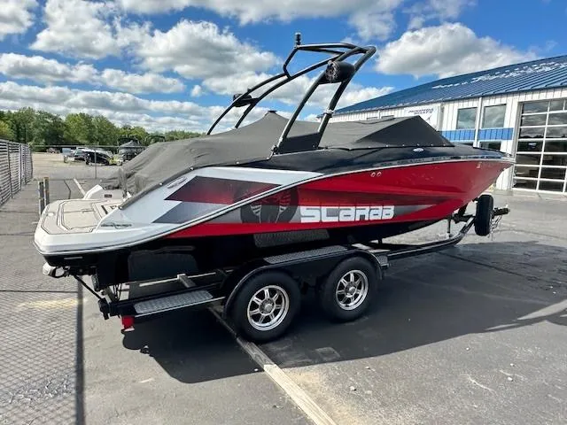 Slide: The Image of 2016 Scarab 215 HO Impulse boat on trailer, red and black, covered, parked outdoors. - 3
