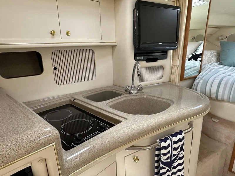 Slide: The Image of 1999 Sea Ray 340 Sundancer interior with kitchenette, sink, stove, and TV. - 3