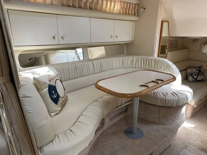 Slide: The Image of Interior of 1999 Sea Ray 340 Sundancer with white seating and wooden table. - 4