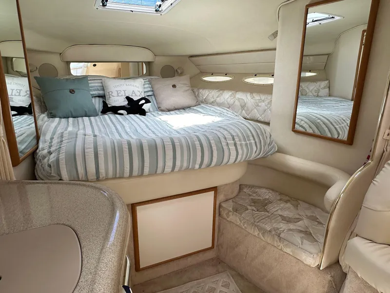 Slide: The Image of 1999 Sea Ray 340 Sundancer cabin with cozy bed, mirrors, and soft lighting. - 6
