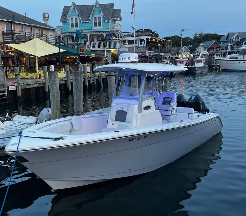 Slide: The Image of 2021 Cobia 262 Center Console boat docked at a lively marina. - 2
