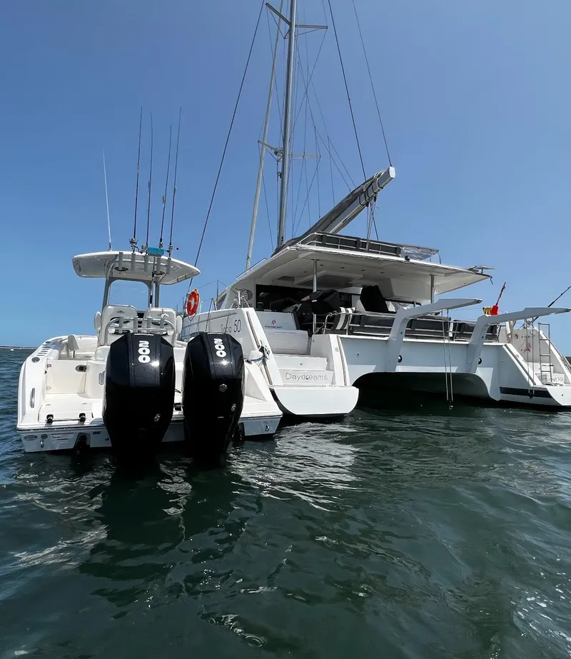 Slide: The Image of 2021 Cobia 262 Center Console boat with twin outboard engines docked beside a large catamaran. - 6