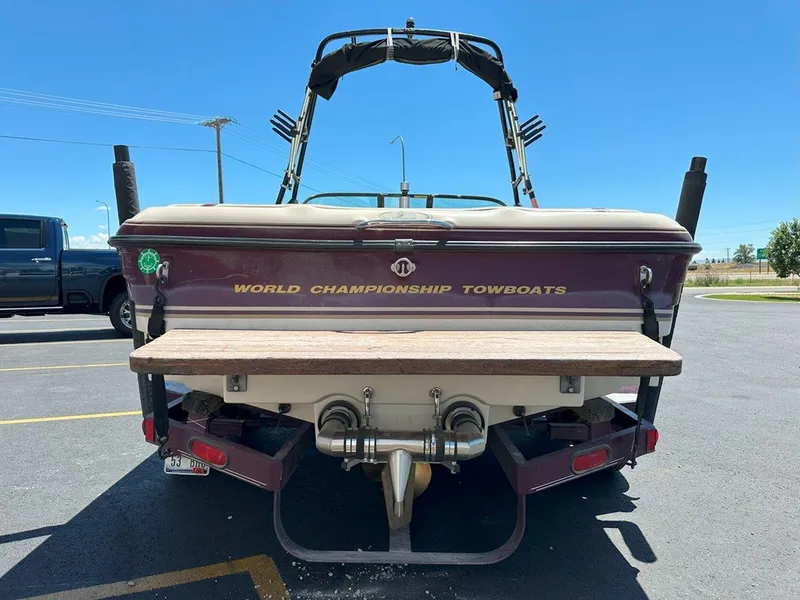 Slide: The Image of 1999 Centurion Elite-V C4 boat, rear view, parked in a lot under clear blue sky. - 7