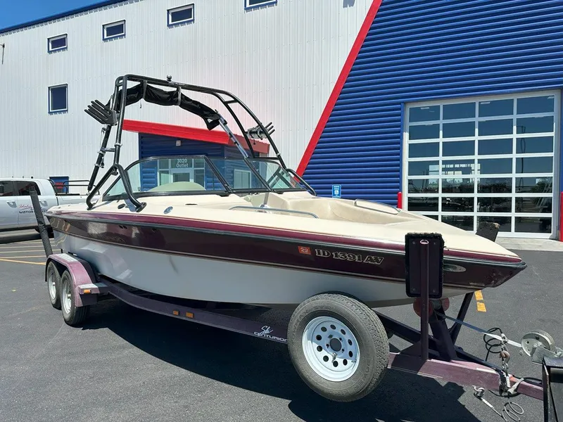 Slide: The Image of 1999 Centurion Elite-V C4 boat on trailer, parked outside a blue and white building. - 9