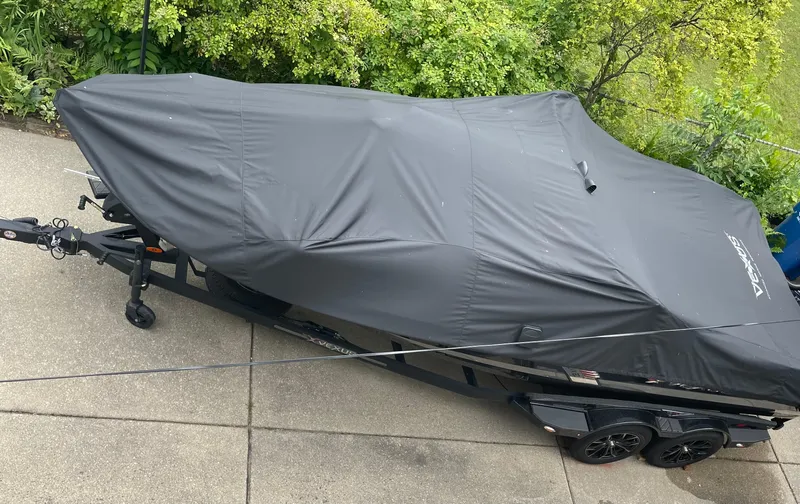 Slide: The Image of 2022 Vexus DVX20 boat with black cover on trailer, parked on concrete driveway. - 14