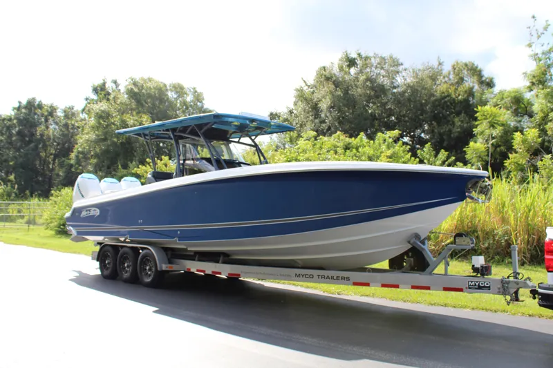 Slide: The Image of 2019 Nor-Tech 340 Sport Center Console boat on trailer, blue hull, parked outdoors. - 1