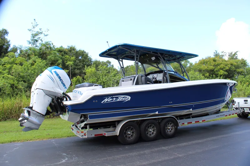 Slide: The Image of 2019 Nor-Tech 340 Sport Center Console boat on trailer, blue hull, triple engines. - 11