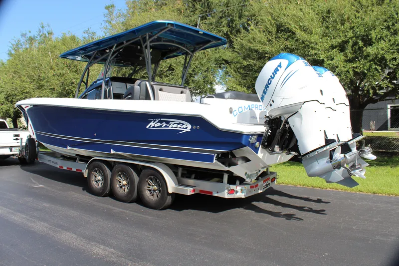 Slide: The Image of 2019 Nor-Tech 340 Sport Center Console boat on trailer, blue hull, triple Mercury engines. - 12