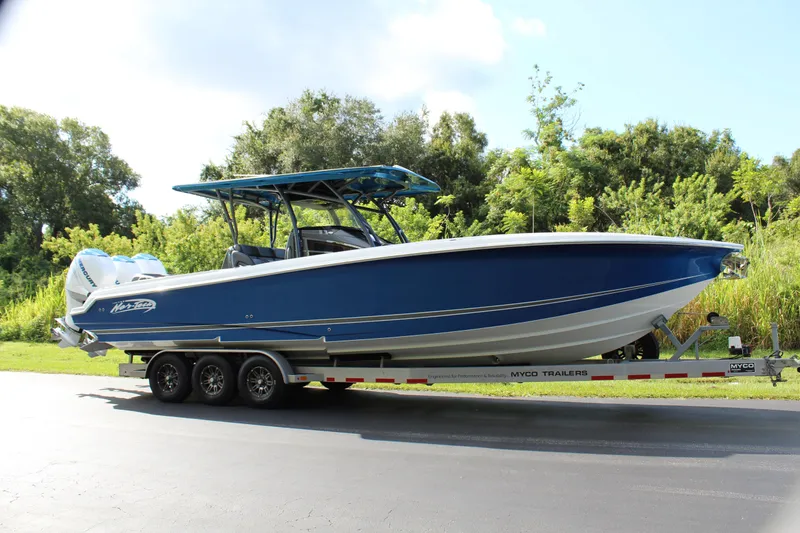 Slide: The Image of 2019 Nor-Tech 340 Sport Center Console boat on trailer, blue hull, parked outdoors. - 3
