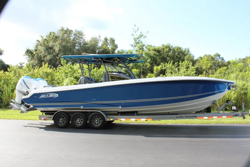 Slide: The Image of 2019 Nor-Tech 340 Sport Center Console boat on trailer, blue hull, parked outdoors. - 4