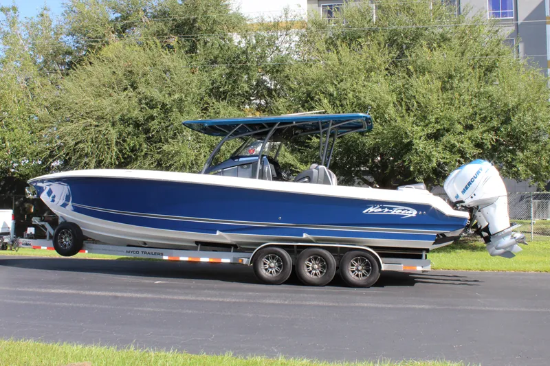Slide: The Image of 2019 Nor-Tech 340 Sport Center Console boat on trailer, blue and white design. - 8