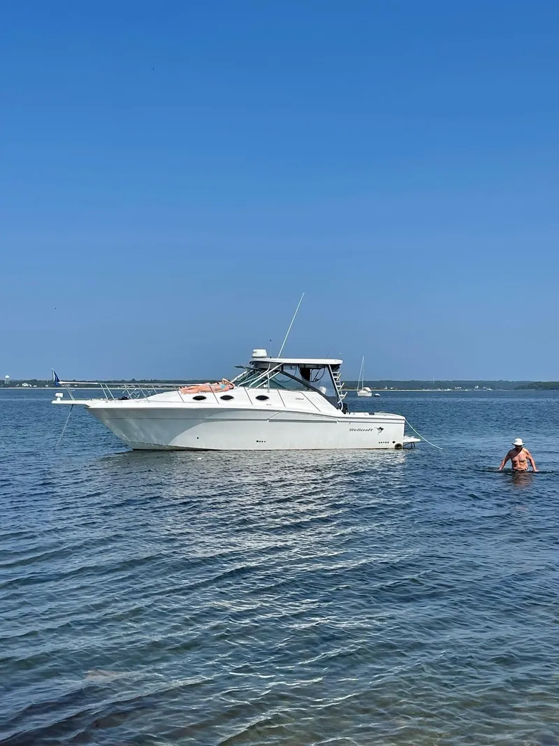 Slide: The Image of 2004 Wellcraft 330 Coastal boat anchored in calm waters under clear blue sky. - 0