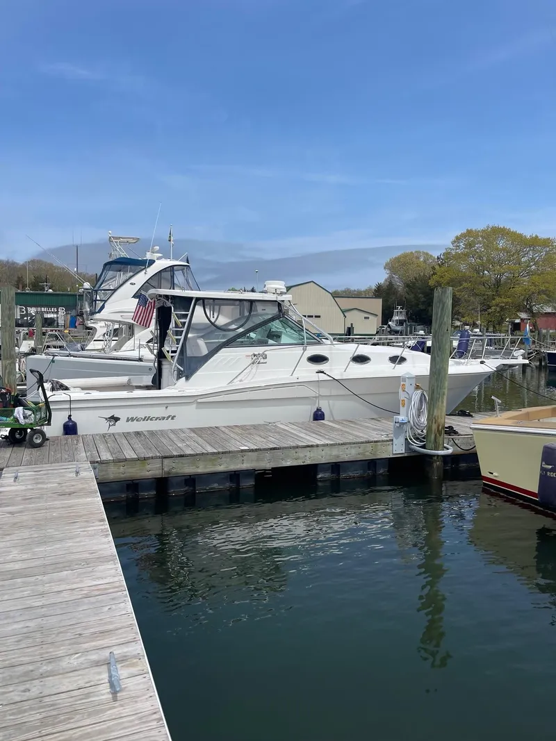 Slide: The Image of 2004 Wellcraft 330 Coastal boat docked at a marina under a clear blue sky. - 1