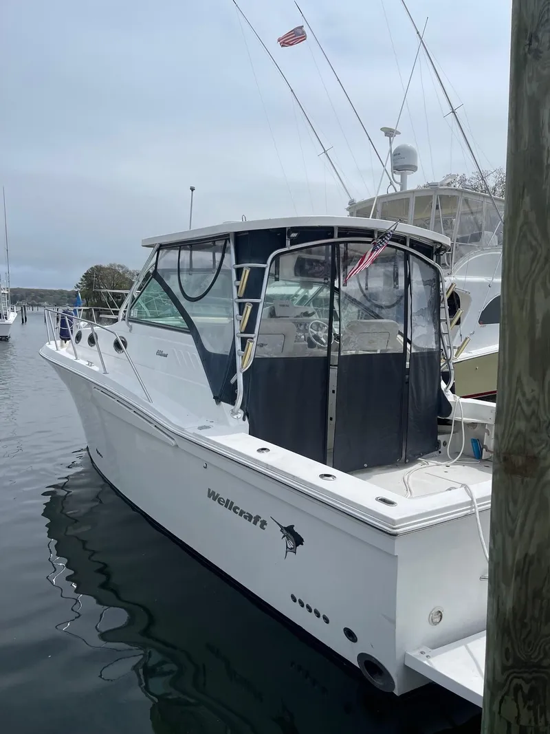 Slide: The Image of 2004 Wellcraft 330 Coastal boat docked in a marina, featuring a sleek white design. - 3